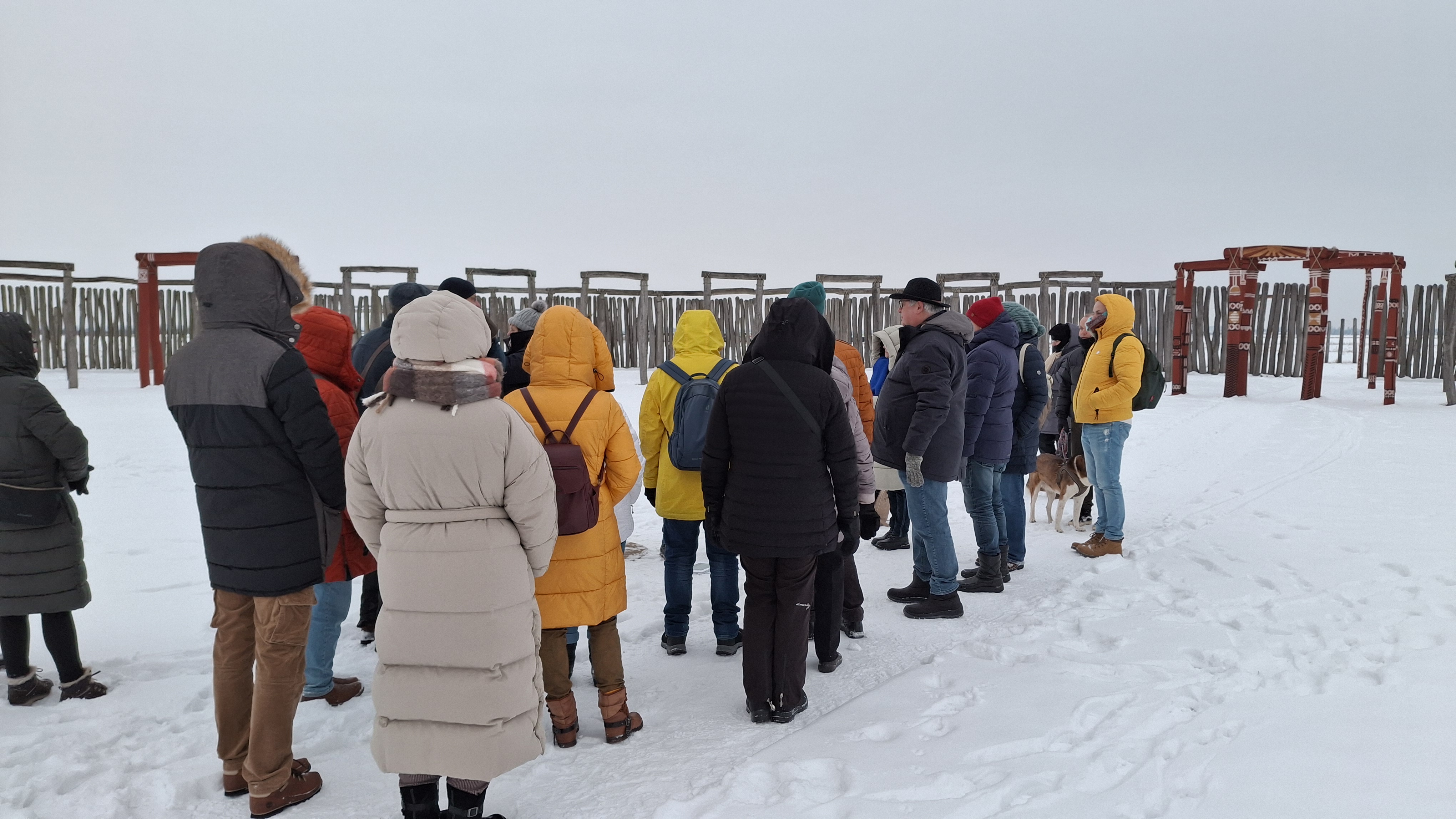 Eine Gruppe Menschen steht bei einer Gästeführung inmitten des schneebedeckten Ringheiligtums.