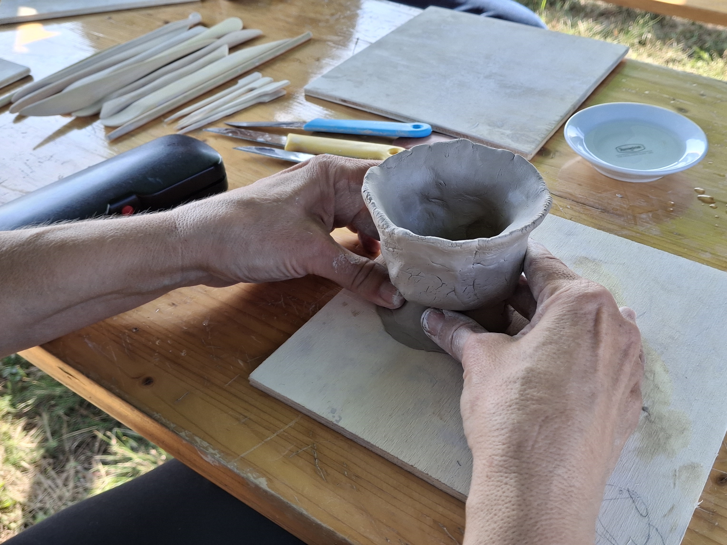 Zwei Hände töpfern ein Gefäß.