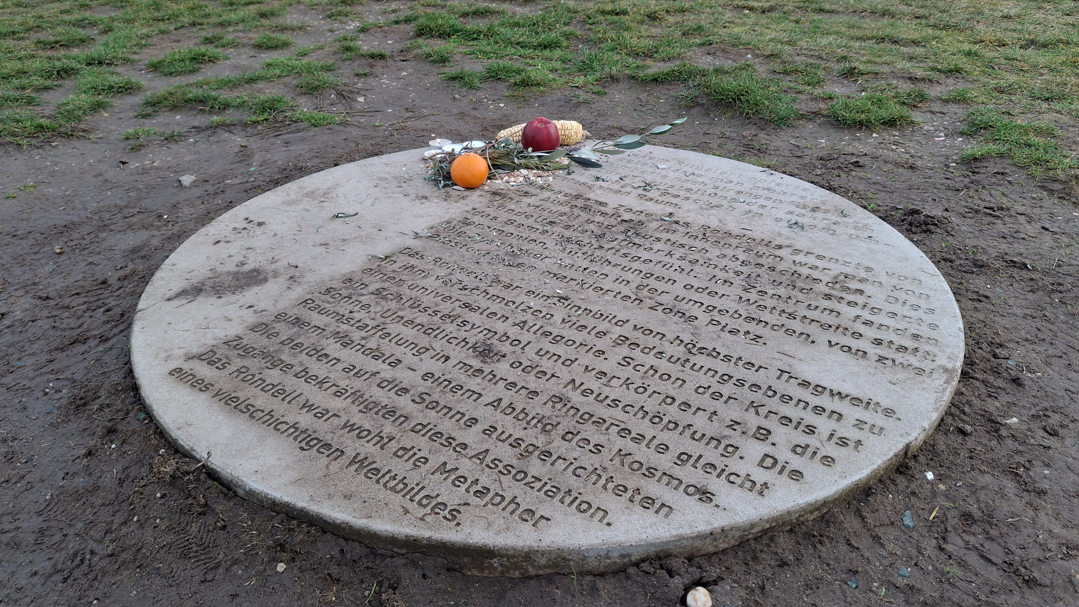 Auf einer runden Steinplatte mit Informationen zum Ringheiligtum wurden "Opfergaben" (Obst und Kerzen) niedergelegt.