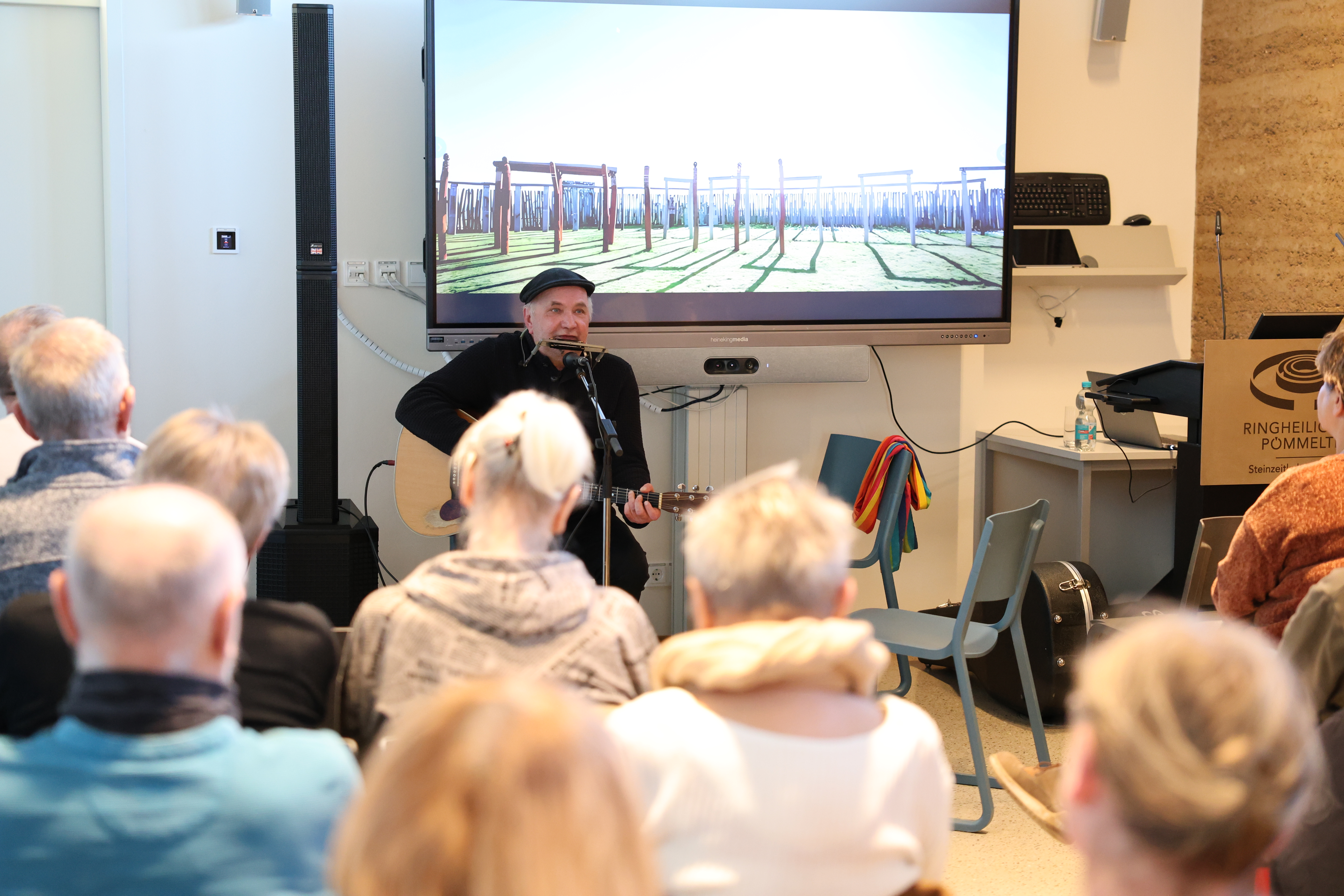 Martin Rühmann spielt Mundharmonika und Gitarre vor einem Publikum.